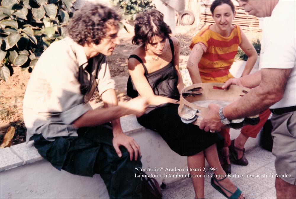 La fotografia a colori immortala un momento di formazione nell'ambito della rassegna annuale “Aradeo e i Teatri” del 1984, alla seconda edizione con il titolo “Concertini”, un appuntamento con il teatro sperimentale che la compagnia del Teatro Koreja, nata nel 1983 nel piccolo borgo salentino di Aradeo, porta avanti sin dall'anno della sua fondazione. Nello specifico si possono osservare diversi musicisti coinvolti nella manifestazione e componenti del gruppo teatrale ‘Gruppo Farfa', diretto dall'attrice danese Iben Nagel Rasmussen, intenti nello suonare alcuni strumenti. Si tratta di un vero e proprio laboratorio per apprendere le tecniche di utilizzo del tamburello, strumento principe della musica salentina, o meglio della pizzica. Spesso questo strumento è accompagna...