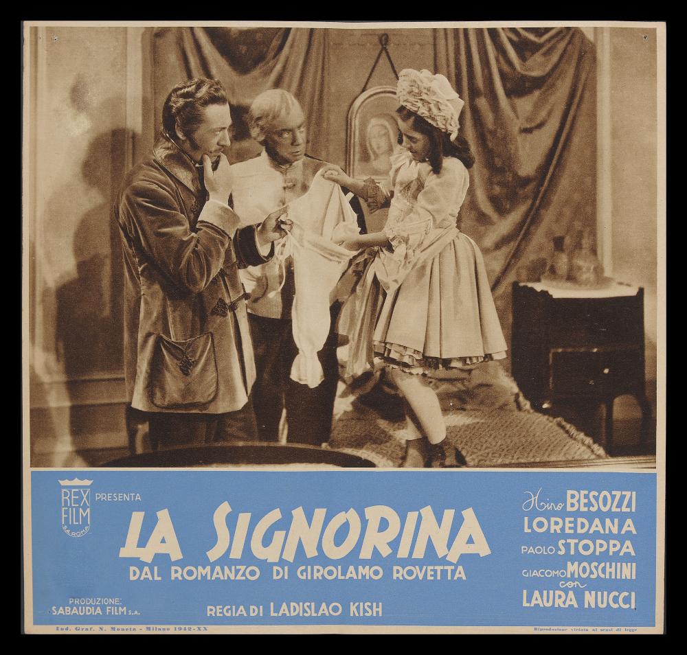 L'immagine riproduce uno dei manifesti conservati presso la Mediateca Regionale Pugliese (vedi Note). Si tratta di uno dei soggetti della fotobusta per il film "La signorina", una commedia sentimentale degli anni '40. La composizione, raffinata ed elegante anche nel titolo, rispecchia i canoni grafici e comunicativi dell'epoca, con una fotografia dai toni del "seppia" presa dalla pellicola che cattura uno dei momenti più significativi del film e racconta il legame che si instaura tra il romanziere e la piccola Lulù. L'opera grafica mostra un bel formato quasi quadrato, un po' diverso dai soliti contenuti nelle fotobuste di stampo rettangolare, certamente più conosciute....