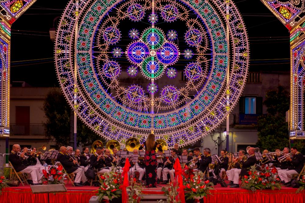 Questo scatto cattura un momento di grande festa e partecipazione in occasione della Festa Patronale di San Niceta a Melendugno, quando importanti e rinomati concerti bandistici si alternano sin dal mattino in “Cassa Armonica”, nella piazza centrale e per le principali vie della Città. In questa foto è protagonista la famosa banda “G. Piantoni“, diretta dalla direttrice Susanna Pescetti. La “G. Piantoni”, composta da 43 musicisti, è una delle bande ai primissimi posti tra le bande dell’intero Mezzogiorno.
La Festa Patronale di San Niceta Goto Martire, istituita nel 1740, si celebra nei giorni 15 e 16 Settembre a Melendugno in provincia di Lecce. Il rito religioso parte nove giorni prima della Festa, con delle celebrazioni eucaristiche presso la chiesa Madre e in forma e...