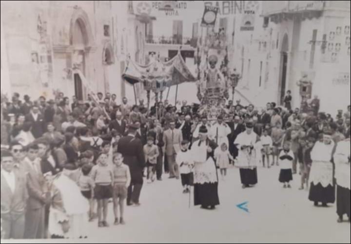 <div class="ql-editor"><div><span>Fotografia storica, di anno non definito, che documenta la processione in onore di </span><strong>San Nicola</strong><span> per le vie di </span><strong>Rutigliano</strong><span>. In primo piano è visibile il busto del Santo patrono, portato in processione tra la partecipazione devota della comunità cittadina. </span></div><div><br></div><div>La <strong>Festa Patronale di Rutigliano</strong> è dedicata a San Nicola e affonda le sue radici nel <strong>1306</strong>, quando Carlo II d’Angiò donò la città al Capitolo della Basilica di San Nicola di Bari, sancendo così il patronato del Santo sulla comunità rutiglianese. I festeggiamenti religiosi e civili si svolgono <strong>nel secondo fine set...