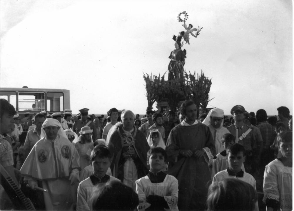 Fotografia storica raffigurante la processione della statua di Santa Cristina. Il simulacro è portato a spalla dai portantini ed è seguito da un corteo composto da sacerdoti e bambini. Si distinguono membri della Confraternita della Purità, riconoscibili dalle vesti bianche e dal mantello recante l’effigie del volto della Santa. Sullo sfondo si intravede la banda cittadina, elemento tradizionale che accompagna musicalmente il corteo processionale.

Gli aspetti storici, religiosi e culturali della festa risultano profondamente radicati nella memoria collettiva dei gallipolini e nella pietà popolare, come attestato dall’impegno costante della Confraternita della Purità nella custodia e trasmissione della tradizione devozionale.
<div><br></div><div>La festa patronale di Sa...
