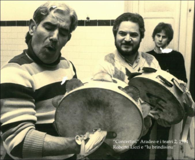 La fotografia in bianco e nero immortala un momento di formazione nell'ambito della rassegna annuale “Aradeo e i Teatri” del 1984, alla seconda edizione con il titolo “Concertini”, un appuntamento con il teatro sperimentale che la compagnia Koreja nata nel 1983 nel piccolo borgo salentino di Aradeo portò avanti sin dall'anno della sua fondazione. Nello specifico si possono osservare Roberto Licci sulla destra e Nicola Carrozzo sulla sinistra, impegnati in un laboratorio di musica con i loro tamburelli. Roberto Licci fu la voce solista del noto Gruppo Canzoniere Grecanico Salentino dal 1974 al 1990, con il quale incise "Canti di Terra d'Otranto e della Grecìa Salentina. Esponente attivo della musica popolare salentina, nel 1984 collaborò ad Aradeo anche con il Gruppo Far...