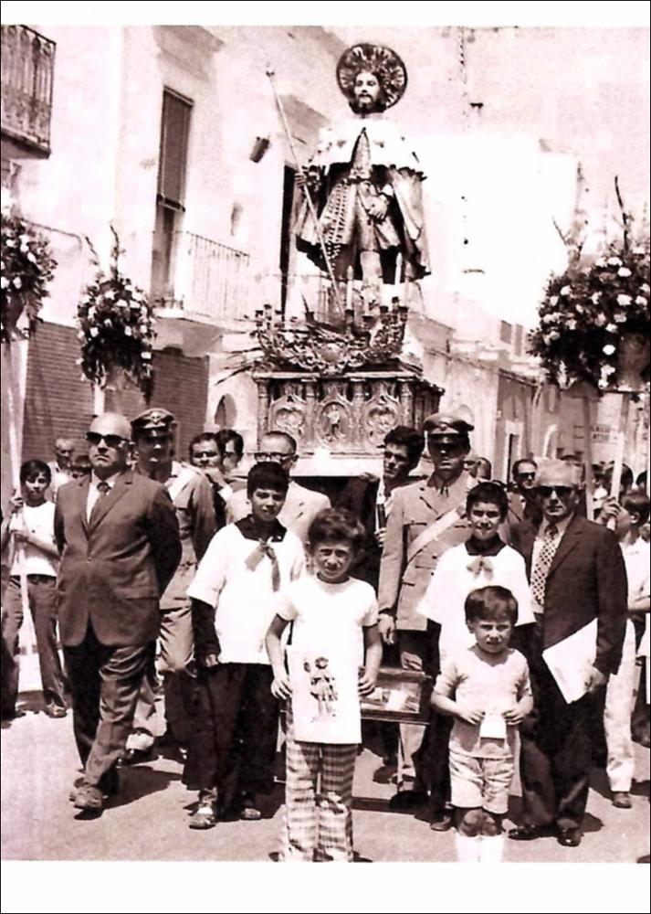 <div class="ql-editor"><div>Fotografia che ritrae la processione di San Rocco lungo via Bari a Valenzano. Un gruppo di bambini accompagna la statua del Santo, in uno dei momenti più solenni e partecipati della Festa Patronale. Anno 1959. La processione attraversa le vie del centro cittadino come espressione di profonda devozione collettiva e memoria storica della comunità di Valenzano.</div><div><br></div><div>La Festa di San Rocco si celebra a Valenzano (BA) il 15, 16 e 17 agosto e affonda le sue radici nel culto patronale, documentato fin dal XVI secolo.</div><div>Dal 2002, la celebrazione si è arricchita del <strong>Corteo Storico Barocco</strong>, che rievoca il voto solenne pronunciato dalla comunità il 27 ottobre 1656, in occasione della peste ...
