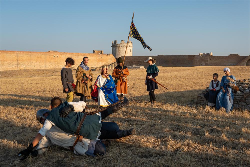 <div>Ricostruzione storica al Villaggio Medioevale 2025 nella Fortezza Svevo-Angioina di Lucera: soldati in armi si fronteggiano davanti al sovrano, mentre un porta bandiera segna la scena, sullo sfondo una coppia di giovani donne tiene un falcone sul braccio, parte dello spettacolo di falconeria che accompagna l’evento. </div><div><br></div><div>Dall’8 al 10 agosto 2025, la Fortezza Svevo-Angioina di Lucera ha ospitato il <strong>Villaggio Medioevale</strong>, cuore narrativo e simbolico della Settimana Medioevale. Allestito all’interno di uno dei complessi fortificati più significativi della Puglia, il Villaggio si è configurato come una vera e propria scenografia vivente, trasformando il monumento in uno spazio attivo capace di restituire ...
