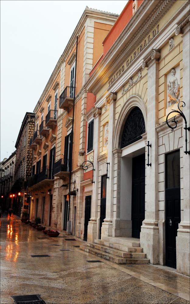 L'immagine è parte della campagna fotografica realizzata dalla fotografa Margherita Mirabella per Teatro Pubblico Pugliese, che ha ripreso nei suoi scatti le eleganti architetture e i rifiniti dettagli di alcuni dei più bei teatri pugliesi e alcuni degli spettacoli teatrali portati in scena in questi ultimi anni. Il Teatro Garibaldi, situato nel borgo antico di Bisceglie tra Piazza Vittorio Emanuele II e Piazza Regina Margherita di Savoia, fu voluto dal governo regio sabaudo, quando fu deliberata la decisione di trasformare gli antichi cameroni della “Polveriera”, dove sorgeva l'antico teatro cittadino costruito sugli ambienti ricavati da uno dei bastioni della cinta muraria. I lavori iniziarono nel 1862 sotto la direzione dell'architetto Giuseppe Albrizio e si concluse...