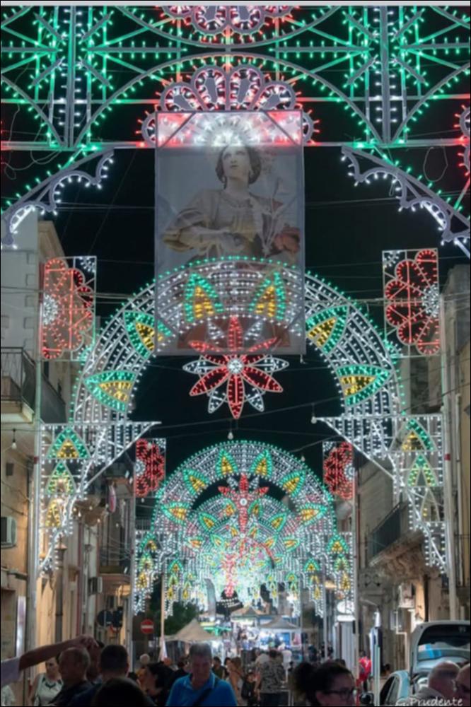 <div class="ql-editor"><div>Strada di Latiano decorata con luminarie per la Festa Patronale di Santa Margherita. Al centro, spicca lo stendardo con il volto della Santa, simbolo della devozione cittadina e del legame tra la comunità e la sua protettrice.</div><div><br></div><div>La Festa Patronale di <strong>Santa Margherita Vergine e Martire</strong>, protettrice di Latiano, è una celebrazione religiosa e civile che unisce devozione, tradizione e identità culturale della comunità. La santa, vissuta tra il 255 e il 275 d.C., è raffigurata come una giovane esile con un drago trafitto dalla croce e una corona di perle sul capo, simbolo del suo coraggio e della sua fede.</div><div>La festa religiosa si celebra il <strong>20 febbraio</strong>, in ri...