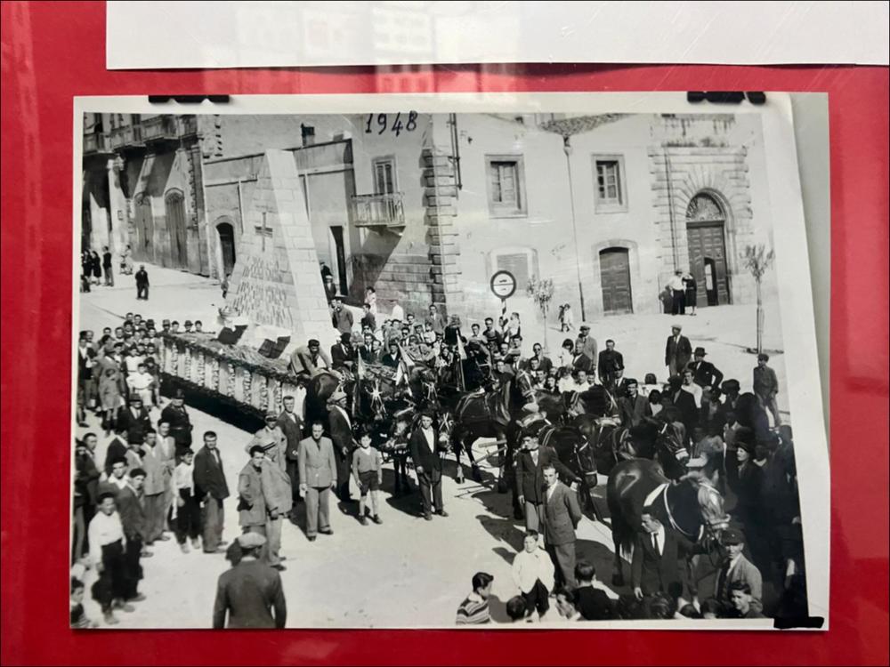 La digitalizzazione di questa foto storica del 1948 mostra uno dei tradizionali carri realizzati per la "Sfilata dei carri votivi".
La sfilata dei carri devozionali (o votivi) addobbati, che rievocano la leggenda del ritrovamento del crocifisso da parte dei contadini, è la principale celebrazione patronale della Festa del SS. Crocifisso di Auricarro a Palo del Colle e viene organizzata ancora oggi nel mese di maggio. I carri di Santa Croce sono strutture artistiche addobbate con forme di carta pesta, fiori e luminarie, rappresentanti temi religiosi, trainati da buoi, cavalli o trattori e realizzati a cura di associazioni, privati o scuole.
La Festa Patronale del SS. Crocifisso di Auricarro, istituita nel 1853, si celebra in due momenti diversi, il 3 Maggio e la terza se...
