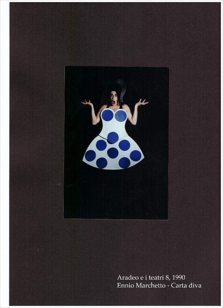 La fotografia a colori cattura un momento dello spettacolo "Carta Diva", rappresentato nel 1990 durante l'ottava edizione di "Aradeo e i Teatri", un appuntamento con il teatro sperimentale che la compagnia Koreja, nata nel 1983 nel piccolo borgo salentino di Aradeo, porta avanti sin dall'anno della sua fondazione. La performance nasce da un'idea originale di Ennio Marchetto, attore, cabarettista, comico, ma soprattutto trasformista italiano. Con la possibilità di scegliere tra oltre 350 personaggi, i suoi show raccontano fatti e fenomeni dell'attualità attraverso il cambio veloce e continuo di figure, costumi, parrucche, accessori, rigorosamente bidimensionali fatti di carta e cartoncino. La sua bravura e le sue doti espressive provengono dalle ispirazioni desunte dai c...