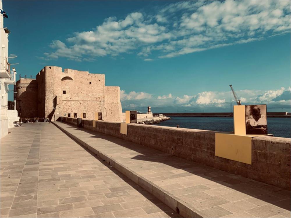 Il lungomare Santamaria, elemento di congiunzione delle coste di Monopoli che raggiunge lo storico Castello di Carlo V, diventa una galleria fotografica con forte richiamo sociale per l’artista Alena Zhandarova (1988, Birobidzhan, Russia), giovane artista russa. Il suo progetto “Hidden Motherhood” vuole far riflettere sul ruolo della donna/madre nella società. I suoi soggetti sono velati così come sono messi sotto un velo le difficoltà e i bisogni della figura femminile. Sono piccole riproduzioni che confrontano il lavoro di Alena con le foto vittoriane (XIX sec.), dove i soggetti principali erano i bambini e non le madri che venivano, nello stesso modo, nascoste....