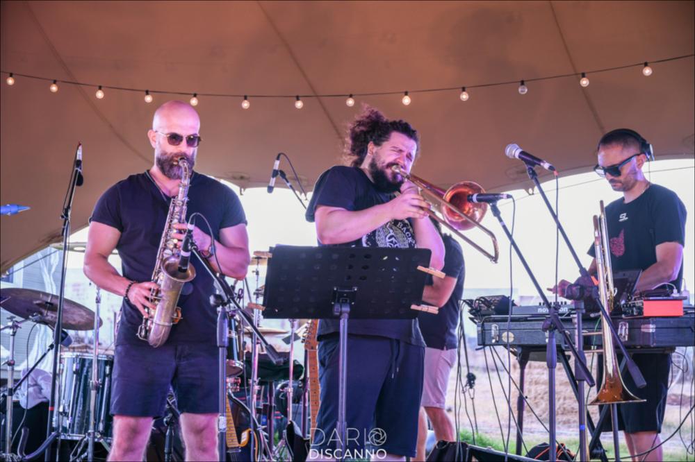 <div>Lo scatto ritrae un momento dello spettacolo musicale “THE NEW WORLD + NAVA” dei Chromophobia, in esibizione nella serata del 25 agosto 2024 presso l’Agribeach di Porto Guaceto in occasione del BPA Festival V Edizione 2024 - Summer Edition. I Chromophobia sono un gruppo musicale elettronico pugliese, nato nel 2018 da David Seta e Nuck. Davide Petiti in arte David Seta è un compositore e polistrumentista (tromba, trombone, chitarra e voce) e Francesco Verardi in arte Nuck è un compositore, dj, producer, e tecnico del suono. I due, entrambi classe ’91, provenienti da diverse formazioni artistiche (il primo dall’ambiente orchestrale, il secondo dalla urban music) iniziano a collaborare nel 2018 come compositori e autori per terz...