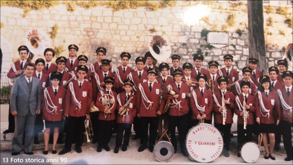 <div class="ql-editor"><div>La digitalizzazione di questa foto mostra il complesso musicale bandistico “Pietro Giannone” di Ischitella (FG) negli anni ‘90.</div><div>Il Corpo Musicale Cittadino “Pietro Giannone” di Ischitella è una storica realtà musicale e culturale del territorio. Composto da strumenti a fiato e a percussione, partecipa a processioni religiose, celebrazioni civili, concerti ed eventi pubblici, custodendo un repertorio che spazia dalle marce sinfoniche alla musica popolare locale.</div><div>Oltre all’attività artistica, il Corpo Musicale svolge un importante ruolo educativo e sociale attraverso corsi e attività rivolti a giovani e adulti. La partecipazione di musicisti di diverse età e livell...
