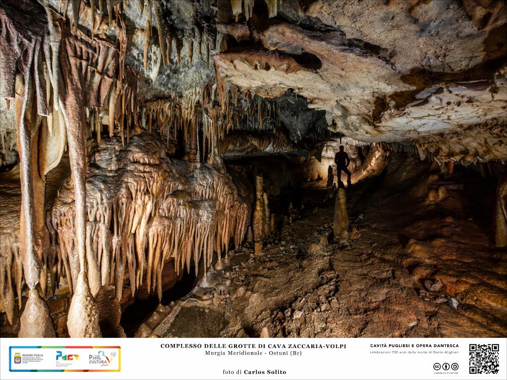 Un’inquietante selva di stalattiti e stalagmiti ostruisce il nostro sguardo, già disorientato dalla moltitudine di cavità e cunicoli nascosti. Ci troviamo nelle profondità sotterranee di Ostuni, l’elegantissima Città Bianca, che custodisce il complesso delle Grotte di Cava Zaccaria-Volpi, che serpeggiano sottoterra per ben 2065 metri.
Le concrezioni calcaree ci offrono una sequenza di sfumature, dal bianco candido del carbonato di calcio più puro, alle tinte più rossastre date dal ferro e dall’alluminio. 
L’immagine digitale fa parte della raccolta di fotografie prodotte da Carlos Solito per il Progetto digitale “Sillabario sotterraneo – Viaggio dantesco nelle Grotte di Puglia” – realizzato nell’ambito della LEGGE REGIONALE 30 dicembre 2020, n. 35 - art. 39 “Cavità pugl...