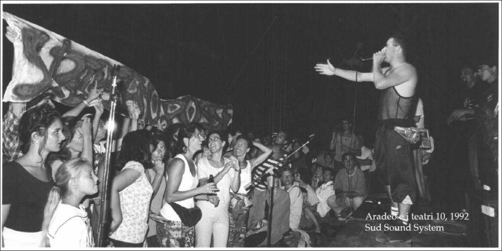 La fotografia in oggetto è stata scattata nel 1992 durante il concerto del gruppo musicale Sud Sound System, all'interno della rassegna annuale “Aradeo e i Teatri”, un appuntamento con il teatro sperimentale che la compagnia Koreja nata nel 1983 nel piccolo borgo salentino di Aradeo porta avanti sin dall'anno della sua fondazione. Con questa festa musicale si concluse la X edizione della kermesse teatrale salentina, svoltasi al Castello Tre Masserie, storica sede della compagnia Koreja. Ad animare la serata un confronto a suon di battute rap tra due tra le più affermate band del genere: i 99 Posse di Napoli e i salentini Sud Sound System, che con la loro musica varcarono i confini locali per approdare, agli inizi degli anni '90, sul mercato della discografia nazionale c...