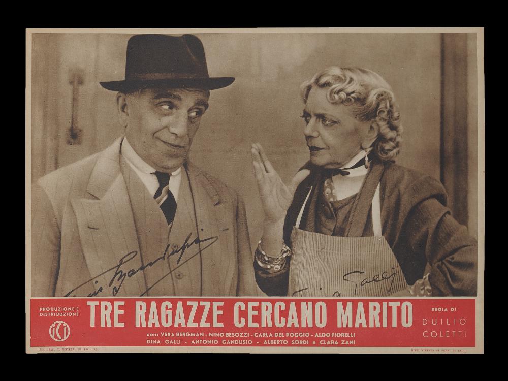 L'immagine riproduce uno dei manifesti conservati presso la Mediateca Regionale Pugliese (vedi Note). Si tratta di uno dei soggetti della fotobusta per il film "Tre ragazze cercano marito", una commedia sentimentale degli anni '40. La composizione, semplice ed elegante, rispecchia i canoni grafici e comunicativi dell'epoca, con una fotografia dai toni del "seppia" presa dalla pellicola che cattura lo sguardo complice della signora Amalia e il Cavalier Luigi, interpretati dagli attori Dina Galli e Antonio Gandusio. Da notare, la particolarità delle firme originali dei due protagonisti, stampate sul manifesto....
