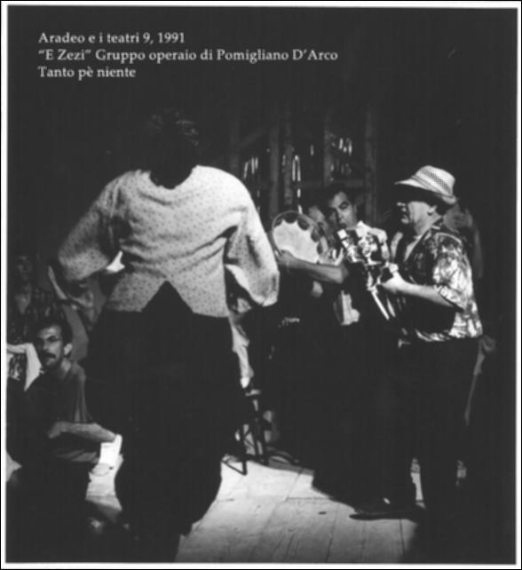 La fotografia in bianco e nero è un momento dello spettacolo "Tanto pè niente", interpretato nel 1991 da "E Zezi - Gruppo operaio di Pomigliano D'Arco" durante la nona edizione di "Aradeo e i Teatri", un appuntamento con il teatro sperimentale che la compagnia Koreja nata nel 1983 nel piccolo borgo salentino di Aradeo portò avanti sin dall'anno della sua fondazione. Quello di "E Zezi" è un gruppo storico di musica popolare napoletana e campana nato negli anni '70 del Novecento per volontà di un gruppo di operai, artigiani e studenti che si fecero interpreti della classe operaia e di un Sud anti-borghese legato alle tradizioni più autentiche, lontane dalla omologazione culturale. La loro unicità consiste anche nell'estendere il repertorio musicale alle altre tradizioni m...