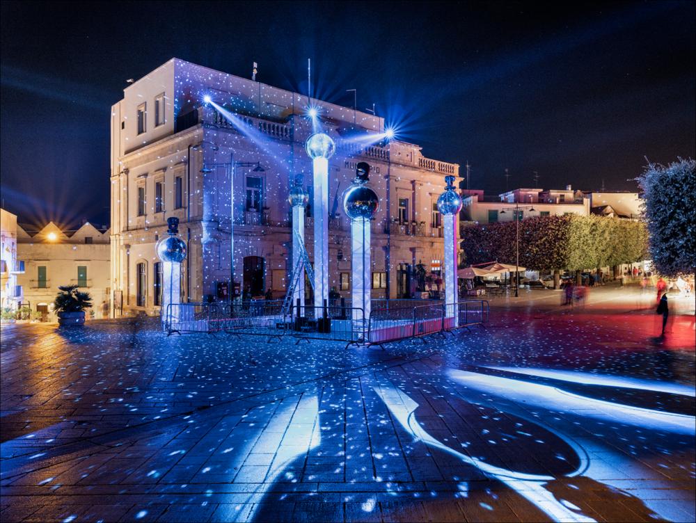 “Fragments of Light - Frammenti di Luce”, opera prodotta da LiFe - Alberobello Light Festival e sviluppata in collaborazione con il visual designer Luigi Console, in piazza del Popolo. Installazione artistica costituita da travi in metallo e sfere riflettenti, che ricreano i riflessi di luce un’atmosfera spaziale quasi uno squarcio sull’universo....