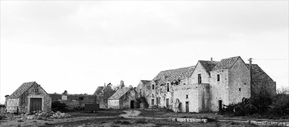 L'istantanea in oggetto, scattata in bianco e nero e successivamente post prodotta, fa parte di una più ampia raccolta di fotografie realizzate per il progetto di censimento di 248 masserie pugliesi avviato da Giancarlo Chielli, professore del corso in Beni Culturali e Ambientali presso l'Accademia di Belle Arti di Bari. Il lavoro svolto ha dato vita al volume “Le masserie di Puglia come Bene Culturale” in cui sono presenti alcuni scatti di masserie pugliesi tra cui questa presa in esame. Questa panoramica da una visione completa di quella che appare oggi Masseria Le Monache, una grande architettura caratterizzata da un ampio complesso costituito da trulli e moduli a pignon. Il complesso si compone di due nuclei di fabbrica, a moduli rettangolare con copertura a pignon,...