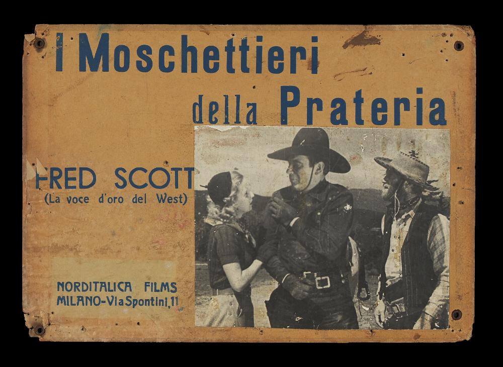 L'immagine riproduce uno dei manifesti conservati presso la Mediateca Regionale Pugliese (vedi Note). Si tratta del soggetto della fotobusta del film "I moschettieri della prateria". La produzione italiana di fotobuste negli anni '30 e '40 comprendeva anche quelle realizzate su supporti cartonati di dimensioni particolari, come in questo caso (24x34) o più genericamente di dimensioni 49x34 circa. Come vediamo da questo esempio, le fotobuste di questo tipo su cartone (che venivano chiamate di tipo "anteguerra") presentano una fotografia di scena in bianco e nero incollata, che aveva la funzione di narrare l'ambientazione del film. Intorno, nello spazio rimanente, con un'illustrazione autonoma, venivano indicate dal grafico le informazioni principali del film (titolo, gen...