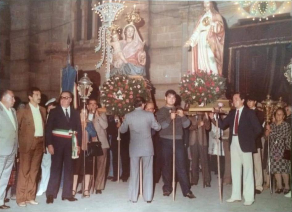 <div class="ql-editor"><div>Foto storica del 1953 che ritrae l’arrivo dei Santi Patroni davanti alla Chiesa Madre di Villa Castelli, nel cuore della Festa Patronale. I simulacri stanno per partire, mentre i portantini, colti in un attimo spontaneo, volgono lo sguardo verso il fotografo, quasi sorpresi dall’obiettivo. In primo piano si distingue la figura del sindaco, segno della partecipazione ufficiale e dell’unione tra istituzioni e comunità.</div><div><br></div><div>La Festa Patronale di <strong>Villa Castelli</strong> si svolge ogni anno dall’1 al 3 ottobre ed è uno degli appuntamenti più attesi e partecipati, non solo dai cittadini ma anche da tante persone provenienti dai paesi vicini. Conosciuta anche in dialetto come “...