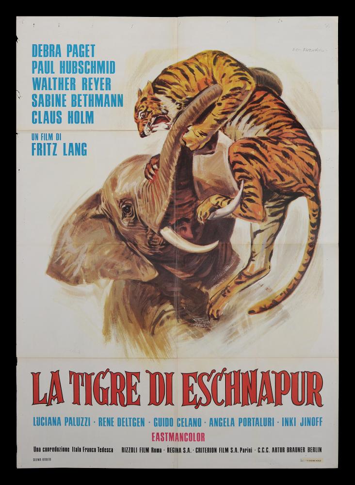L'immagine riproduce uno dei manifesti conservati presso la Mediateca Regionale Pugliese (vedi Note). Si tratta di una delle versioni grafiche del manifesto del film “La tigre di Eschnapur”, del 1959 per la regia di Fritz Lang, a firma di Ezio Tarantelli, come si legge ponendo l’attenzione in alto a destra. Noto per la produzione di illustrazioni per film minori e quelli del genere "Spaghetti western", Ezio Tarantelli è un artista e grafico, fondatore dello Studio E2 insieme al collega Enzo Sciotti. La composizione grafica è molto ordinata e lo sfondo bianco esalta l’immagine molto realistica, della lotta fra l’elefante e la tigre. Composizione molto simmetrica, è dettata nella parte centrale dall’elefante. In basso, vi è il titolo in stampatello rosso e sotto in azzurr...