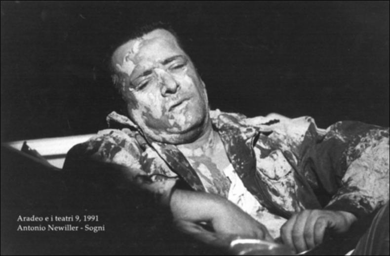 La fotografia in bianco e nero è un momento dello spettacolo "Sogni", rappresentato nel 1991 da Antonio Neiwiller durante la nona edizione di "Aradeo e i Teatri", un appuntamento con il teatro sperimentale che la compagnia nata nel 1983 nel piccolo borgo salentino di Aradeo porta avanti sin dall'anno della sua fondazione. Lo spettacolo fu proposto come evento speciale ed esclusivo per la prima volta proprio in quell'anno, insieme a "Sfigurato" di Alfonso Santagata. "Sogni" è l'idea di Sud di Neiwiller, che semisepolto nella terra e ricoperto di rifiuti come un barbone narra lamentoso storie e microstorie di rabbia e infelicità permanente fondata sul sopruso. La suggestione di un mondo sempre più degradato (per l'ambiente e gli umani indistintamente) è data da una scenog...