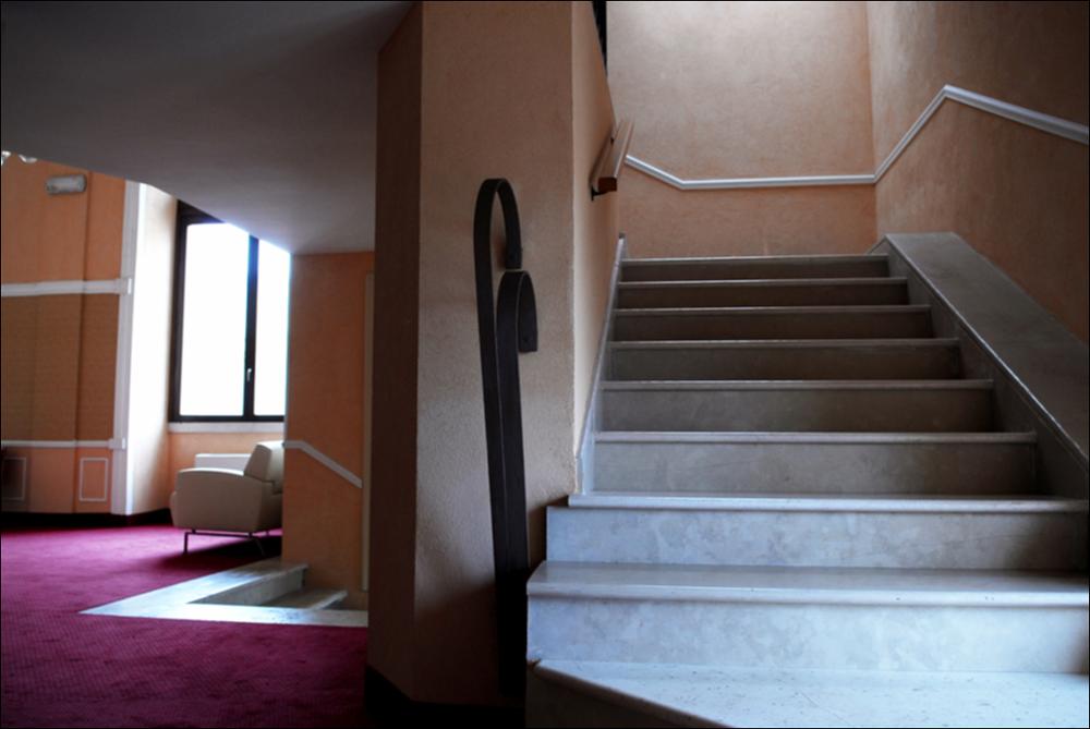 L'immagine è parte della campagna fotografica realizzata dalla fotografa Margherita Mirabella per Teatro Pubblico Pugliese, che con i suoi scatti ha ripreso le eleganti architetture e i rifiniti dettagli di alcuni dei più bei teatri pugliesi e di alcuni spettacoli teatrali portati in scena in questi ultimi anni. La fotografia è stata realizzata all'interno del Teatro Comunale Tommaso Traetta di Bitonto, un piccolo gioiello che, nonostante i rimaneggiamenti posticci dovuti ad interventi di restauro moderni, conserva nella struttura iniziale e nei decori, l'originario schema dei classici teatri all'italiana ottocenteschi. La struttura teatrale, intitolata solo nel 2005 al musicista bitontino Tommaso Traetta, fu voluta dalle famiglie notabili della città che, negli anni Tr...