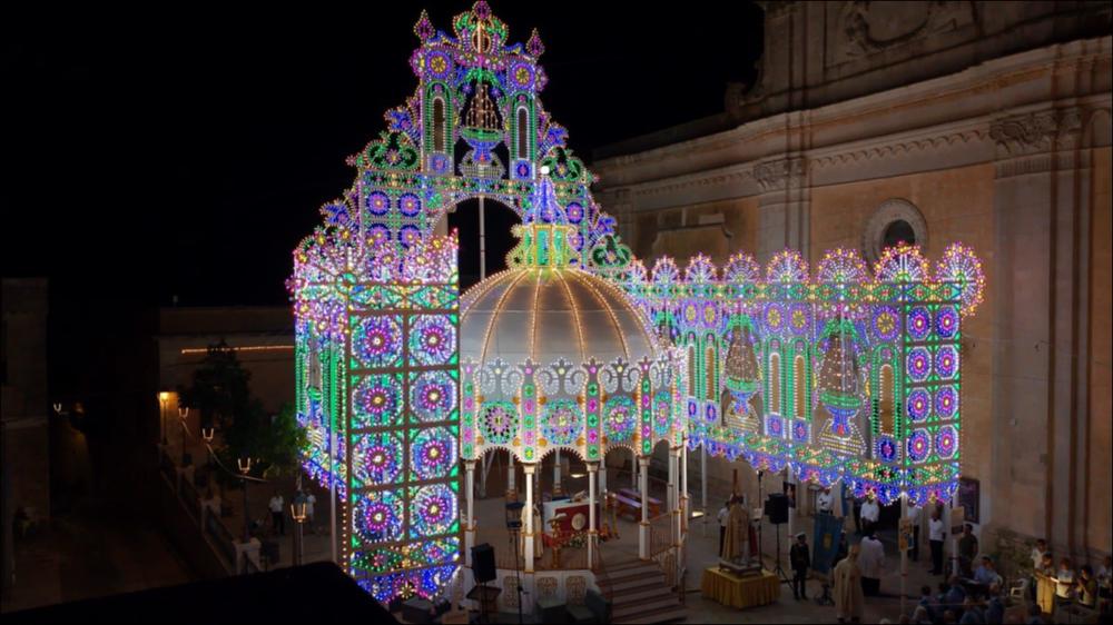 <div class="ql-editor"><div>Lo scatto fotografico immortala il suggestivo allestimento della Cassarmonica per la celebrazione della Messa al suo interno, in occasione della festa di San Nicola, patrono della città di Salve (Le).</div><div>La festa patronale della parrocchia di Salve è dedicata a San Nicola, qui venerato col titolo di “Magno”.</div><div>La festa, negli ultimi anni, ha assunto una dicitura dialettale: <strong>La festa de Santu Nicola.</strong></div><div>Il culto in onore di San Nicola a Salve affonda le sue radici nei secoli passati e si diffonde a partire dalla seconda metà del Cinquecento. Un documento del 1567, redatto da don Francesco Valentini, parroco dell’epoca, attesta che i battesimi venivano celebrati «nella...