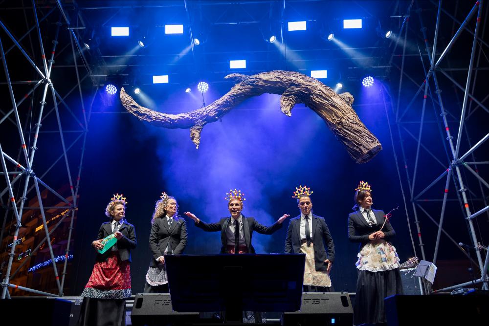 <p class="ql-align-justify">La fotografia ritrae l’energia e l’ironia di “Le Propaggini”, il tradizionale festival in vernacolo che ha aperto la 630^ edizione del Carnevale di Putignano il 26 dicembre. Sul palco di Largo Porta Nuova, otto gruppi di poeti irridenti hanno animato il pubblico con rime pungenti e satira locale, celebrando l’antica tradizione contadina che da secoli anima la città. L’immagine cattura il momento in cui i propagginanti, tra costumi colorati e sorrisi contagiosi, portano avanti la festa che unisce storia, divertimento e spirito di comunità.</p>...