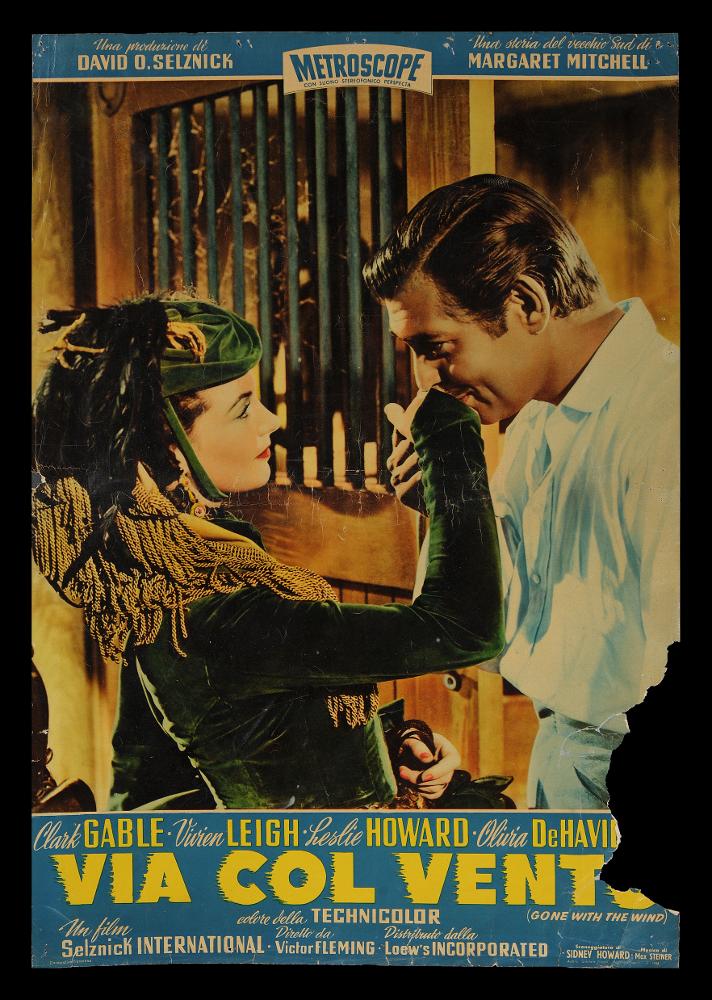 L'immagine riproduce uno dei manifesti conservati presso la Mediateca Regionale Pugliese (vedi Note). Si tratta di una delle fotografie di scena usate per le fotobuste del film "Via col vento" colossal del 1939 per la regia di Victor Fleming, adattamento cinematografico dell’omonimo romanzo di Margaret Mitchell del 1936. Sulla scena i due protagonisti principali, la bellissima Vivien Leigh, nei panni Rossella O'Hara volitiva figlia del proprietario di una piantagione della Georgia, e Clark Gable, l’affascinante Rhett Butler immortalati durante un seducente baciamano....