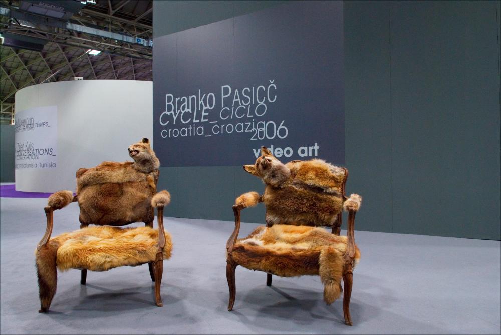 L'immagine digitale documenta un momento della "Biennale dei Giovani Artisti dell'Europa e del Mediterraneo" che, nella sua XIII edizione, fu ospitata in Puglia, a Bari, dal 22 al 31 maggio 2008 negli spazi della Fiera del Levante. La Biennale è considerata la più importante vetrina in Europa e nel Mediterraneo per la creatività delle giovani generazioni. Voluta da Regione Puglia e dall'Associazione Internazionale BJCEM e realizzata dal Teatro Pubblico Pugliese, la Biennale ha dato così spazio ad una visione multidisciplinare, multiforme e internazionalizzata dell'arte contemporanea attraverso creazioni di musica, arti visive, teatro, video, arti applicate, letteratura e gastronomia. Scattata a luce ambiente in uno degli spazi della Fiera, la fotografia immortala una de...