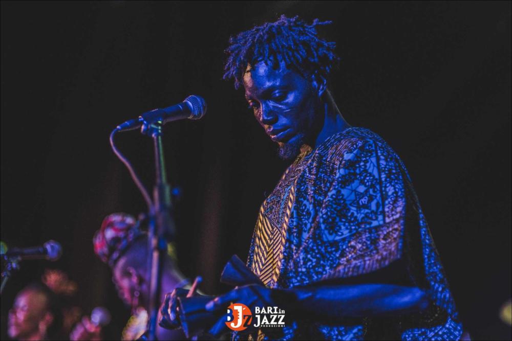 "Bari in Jazz" è un Festival Metropolitano con cadenza annuale, organizzato da Abusuan in Puglia, presenta concerti con ospiti nazionali ed internazionali. L’edizione 2018 del Festival Metropolitano "Bari in Jazz", la quattordicesima, è stata interamente dedicata alle figure femminili nella musica e nel jazz, nel canto, nella composizione e nell’arrangiamento, nell’uso dei vari strumenti e stili musicali. Come ogni anno il Festival Metropolitano Bari in Jazz, luogo d’incontro della musica jazz con altri generi musicali, offre una vetrina d’eccellenza alle grandi artiste e a quelle emergenti, promuovendo anche nuove creazioni. La fotografia mostra un componente della band, in abiti tipici, mentre suona uno strumento particolare. La luce fredda (blu) prevale nella fotogra...