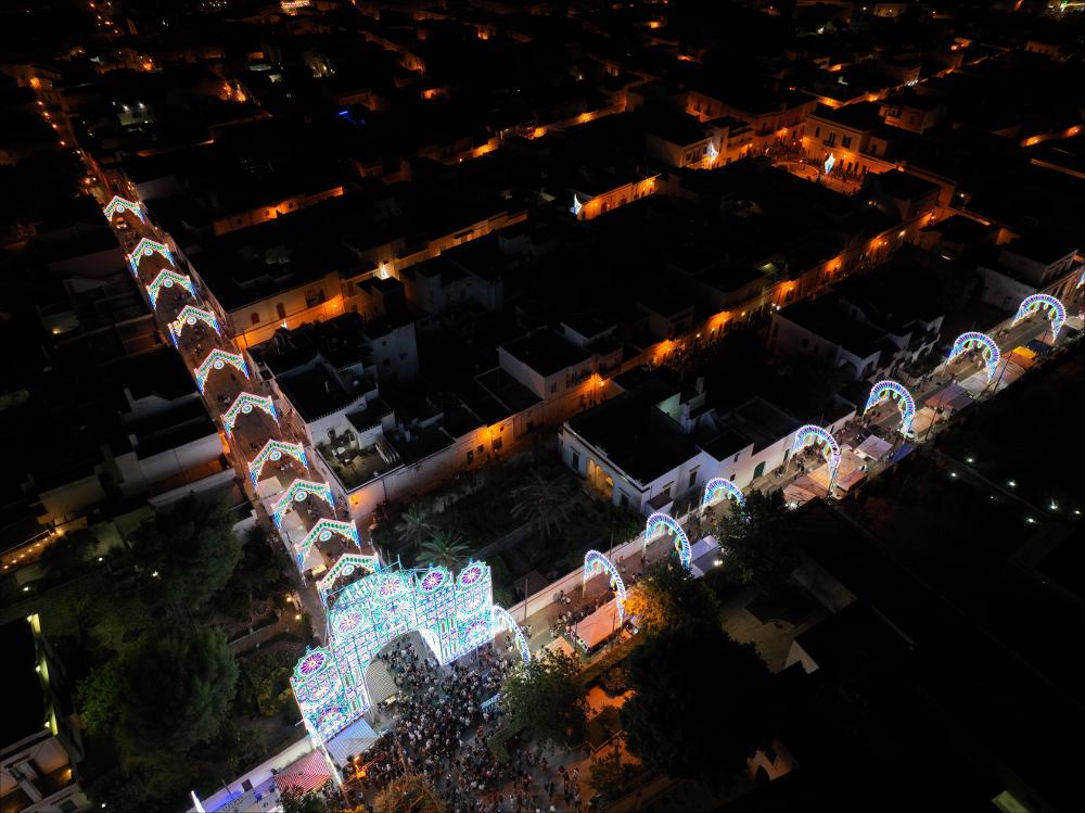 <div class="ql-editor"><div>Suggestiva immagine dall'alto delle luminarie allestite in occasione della Festa Patronale in onore di Santa Maria della Lizza ad Alezio.</div><div>Questa Festa rappresenta il momento più solenne e significativo del calendario religioso e civile della comunità di Alezio, piccolo centro del Salento in provincia di Lecce. Si celebra ogni anno il 14, 15 e 16 agosto e si distingue per la profonda devozione popolare, l’intensità delle celebrazioni liturgiche e la ricchezza delle manifestazioni civili e culturali che la accompagnano.</div><div>Fulcro della festa sono i riti religiosi in onore di Santa Maria della Lizza, Patrona di Alezio, venerata nell’omonimo Santuario risalente al XII secolo. Particolarmente suggestiva ...