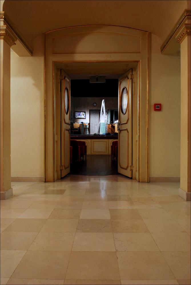 L'immagine è parte della campagna fotografica realizzata dalla fotografa Margherita Mirabella per Teatro Pubblico Pugliese, che ha ripreso nei suoi scatti le eleganti architetture e i rifiniti dettagli di alcuni dei più bei teatri pugliesi e alcuni degli spettacoli teatrali portati in scena in questi ultimi anni. Con questo scatto entriamo idealmente dal foyer all'interno della platea del piccolo ed elegante Teatro Comunale di Mola di Bari, intitolato al suo più celebre cittadino, il compositore Niccolò Van Westerhout. Iniziati nel 1888 per volere dell'Amministrazione comunale, i lavori per la sua edificazione si conclusero nel 1896; il teatro era pronto così ad ospitare sul suo palco il 18 aprile l'opera “Doña Flor” che Van Westerhout dedicò a Mola, la sua città nativa...