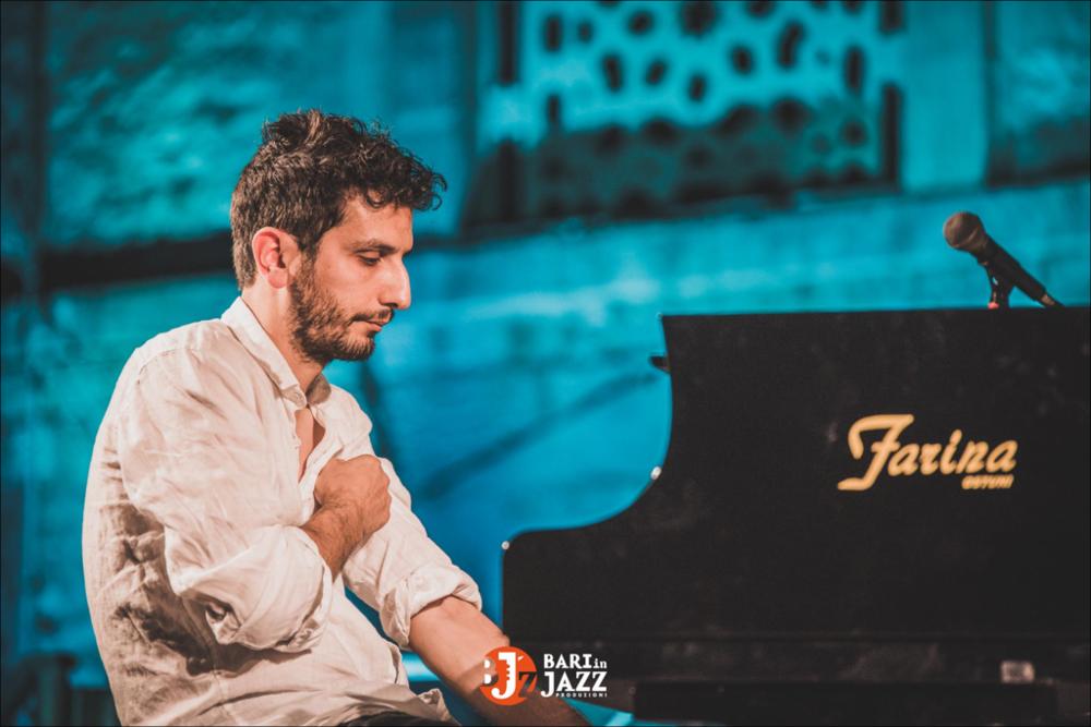 "Bari in Jazz" è un Festival Metropolitano con cadenza annuale, organizzato da Abusuan in Puglia, presenta concerti con ospiti nazionali ed internazionali. L’edizione 2018 del Festival Metropolitano "Bari in Jazz", la quattordicesima, è stata interamente dedicata alle figure femminili nella musica e nel jazz, nel canto, nella composizione e nell’arrangiamento, nell’uso dei vari strumenti e stili musicali. Come ogni anno il Festival Metropolitano Bari in Jazz, luogo d’incontro della musica jazz con altri generi musicali, offre una vetrina d’eccellenza alle grandi artiste e a quelle emergenti, promuovendo anche nuove creazioni. La fotografia mostra un pianista nell'attimo prima di iniziare a suonare, si prepara, guarda il pianoforte. Quest'ultimo occupa metà dello scatto,...