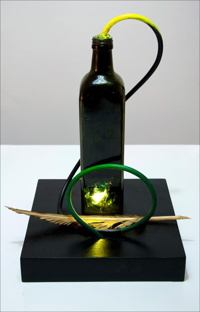 L'immagine digitale riproduce un'opera dell'artista pugliese Gianni De Serio. Classe 1972, la sua carriera artistica comincia in seguito alla laurea in Arti visive conseguita nel 2011, dopo anni da web project manager e graphic design. Le sue opere sono il risultato di una ricerca stilistica che predilige l'ibridazione di linguaggi: pittura, grafica, fotografia, multimedia e videomaking. Seppur talvolta oniriche, le sue opere nascondono sempre una riflessione sulle cose quotidiane, sulle origini, sull'uomo e le sue relazioni e sulla realtà seppur rivista, in una trasfigurazione di se stessa. L'opera è una installazione con un lume ed una penna d'oca, eseguita appositamente per la rassegna d'arte “Olio d'artista”, curata dall'artista Franco Sannicandro che dal 2011 invit...