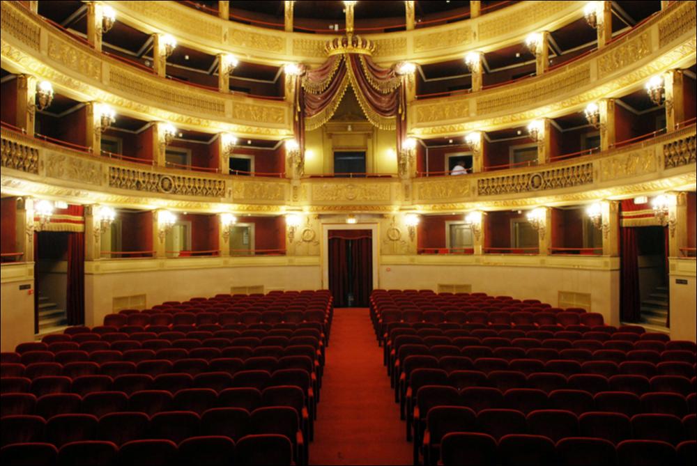 L'immagine è parte della campagna fotografica realizzata dalla fotografa Margherita Mirabella per Teatro Pubblico Pugliese, che con i suoi scatti ha ripreso le eleganti architetture e i rifiniti dettagli di alcuni dei più bei teatri pugliesi e di alcuni spettacoli teatrali portati in scena in questi ultimi anni. In foto la platea del Teatro Comunale Niccolò Piccini, la più antica struttura teatrale della città di Bari. I lavori di costruzione del teatro furono avviati nel 1836 su progetto dell'architetto Antonio Niccolini e ultimati nel 1854; nello stesso anno fu inaugurato con l'allestimento del Poliuto di Gaetano Donizetti e nel 1855 venne dedicato al compositore barese Niccolò Piccini. Il Piccinni è il quarto teatro all'italiana più grande di Puglia dopo il Petruzzel...