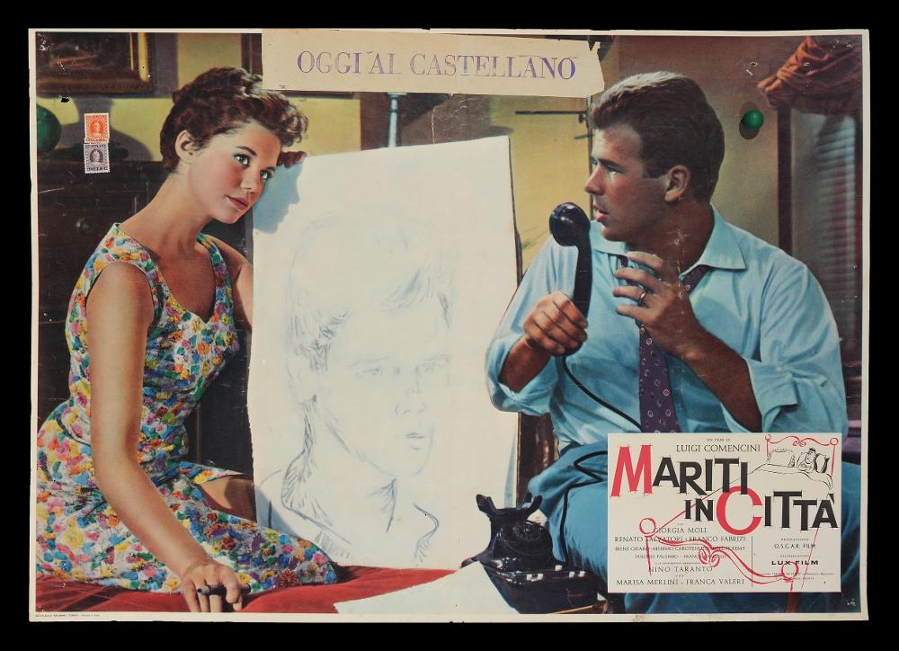 L'immagine riproduce uno dei manifesti conservati presso la Mediateca Regionale Pugliese (vedi Note). Si tratta di una delle versioni delle fotobuste del film di Luigi Comencini “Mariti in città” del 1957. La fotografia di scena riprende una scena al chiuso, in appartamento, con due dei protagonisti. In basso a destra, in rettangolo, quasi su una cartolina, sono riportate a stampa alcune informazioni sul film come il titolo, il cast e i credits, inoltre vi è anche una immagine dai soli contorni di un letto con un uomo/marito solo....