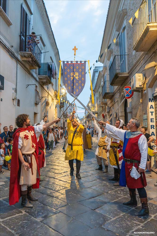 <div>Il corteo storico percorre le vie di Lucera come un racconto in movimento: in testa lo stemma del Torneo delle Chiavi, portato dalla vincitrice Porta Foggia, seguito da cavalieri e figuranti in abiti medievali, avvolti nei colori delle antiche casate. Il ritmo della sfilata e la ricchezza dei costumi restituiscono alla città l’atmosfera di un tempo, trasformando lo spazio urbano in un luogo di memoria, identità e tradizione condivisa.</div><div><br></div><div>Il 13 agosto 2025, il <strong>Corteo Storico di Lucera</strong> ha animato le vie del centro, con partenza dalla Fortezza Svevo-Angioina e arrivo in piazza Duomo. La sfilata ha visto la partecipazione straordinaria di Sergio Muniz nelle vesti di re Carlo II d’Angiò e ha coinvolto olt...