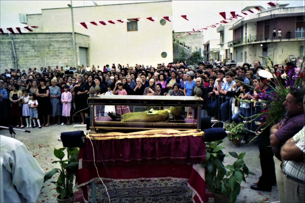In questo scatto del 1982 una folla di devoti si raccoglie in preghiera attorno al Corpo del Santo Patrono Niceta: sono momenti intensi di fede e devozione popolare. Nel 1982, si è celebrato il centenario della traslazione della reliquia di San Niceta a Melendugno.
La Festa Patronale di San Niceta Goto Martire, istituita nel 1740, si celebra nei giorni 15 e 16 Settembre a Melendugno in provincia di Lecce. Il rito religioso parte nove giorni prima della Festa, con delle celebrazioni eucaristiche presso la chiesa Madre e in forma esclusiva viene celebrata la santa messa in rito bizantino presso l’Abbazia di San Niceta situata in Melendugno sin dal 1167, riconosciuta appunto come uno dei più importanti riferimenti storici del territorio.
Il giorno della vigilia della Festa...