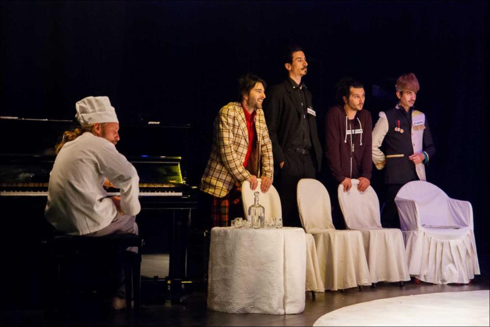 L'immagine in oggetto, fotografia digitale ad opera di Angela Chezzi, cattura un momento dello spettacolo “Il Matrimonio”, per la regia di Salvatore Tramacere, tratto dall'opera teatrale del 1842 di Nikolaj Vasil'evič Gogol', satira incentrata su una giovane donna, Agafija, corteggiata da quattro scapoli, ognuno con le sue eccentricità. Gli stessi personaggi vengono catapultati da Tramacere nel nostro tempo, portando con sé i lati più buffi e divertenti. Il palcoscenico ricorda un set di una trasmissione televisiva, con un presentatore che guida uomini e donne nella ricerca del partner, ma tutto risulta finto e lo schermo allontana ancor più i protagonisti, lasciandoli soli con le proprie inquietudini, aumentando così la distanza tra l'essere e l'apparire. Per far sposa...