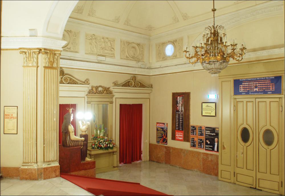 L'immagine è parte della campagna fotografica realizzata dalla fotografa Margherita Mirabella per Teatro Pubblico Pugliese, che con i suoi scatti ha ripreso le eleganti architetture e i rifiniti dettagli di alcuni dei più bei teatri pugliesi e di alcuni spettacoli teatrali portati in scena in questi ultimi anni. La fotografia ritrae il foyer del Teatro Comunale Niccolò Piccini, la più antica struttura teatrale della città di Bari. I lavori di costruzione del teatro furono avviati nel 1836 su progetto dell'architetto Antonio Niccolini e ultimati nel 1854; nello stesso anno fu inaugurato con l'allestimento del Poliuto di Gaetano Donizetti e nel 1855 venne dedicato al compositore barese Niccolò Piccini. Il Piccinni è il quarto teatro all'italiana più grande di Puglia dopo ...
