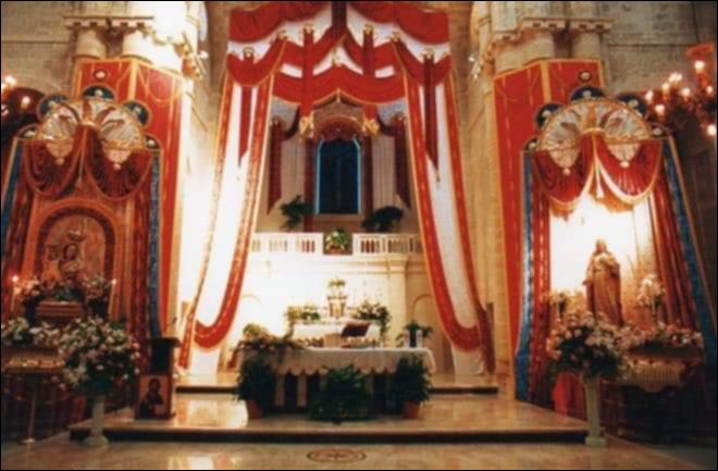 <div class="ql-editor"><div>L’interno della <strong>Chiesa Madre</strong> si trasforma in un vero e proprio scrigno di devozione durante la Festa Patronale. Fiori freschi, drappi colorati e candele illuminano l’altare e le navate, richiamando l’attenzione sui <strong>Santi Patroni</strong>, il <strong>Sacro Cuore di Gesù</strong> e la <strong>Madonna della Fontana</strong>.</div><div>I colori scelti riflettono la solennità e l’affetto della comunità: il rosso per il Sacro Cuore di Gesù, simbolo di amore e misericordia, e il bianco e azzurro per la Madonna della Fontana, a richiamare purezza, protezione e devozione popolare. Ogni dettaglio, dai ceri accesi alle composizioni floreali, è pensato per guidare i fedeli nella pr...