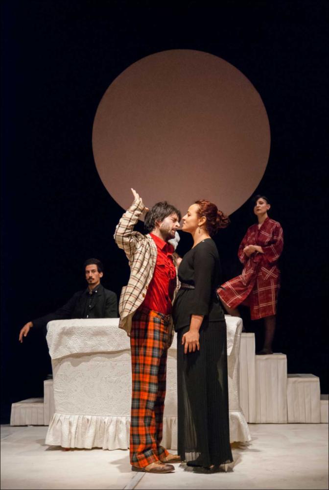 L'immagine in oggetto, fotografia digitale ad opera di Angela Chezzi, cattura un momento dello spettacolo “Il Matrimonio”, per la regia di Salvatore Tramacere, tratto dall'opera teatrale del 1842 di Nikolaj Vasil'evič Gogol', satira incentrata su una giovane donna, Agafija, corteggiata da quattro scapoli, ognuno con le sue eccentricità. Gli stessi personaggi vengono catapultati da Tramacere nel nostro tempo, portando con sé i lati più buffi e divertenti. Il palcoscenico ricorda un set di una trasmissione televisiva, con un presentatore che guida uomini e donne nella ricerca del partner, ma tutto risulta finto e lo schermo allontana ancor più i protagonisti, lasciandoli soli con le proprie inquietudini, aumentando così la distanza tra l'essere e l'apparire. Per far sposa...