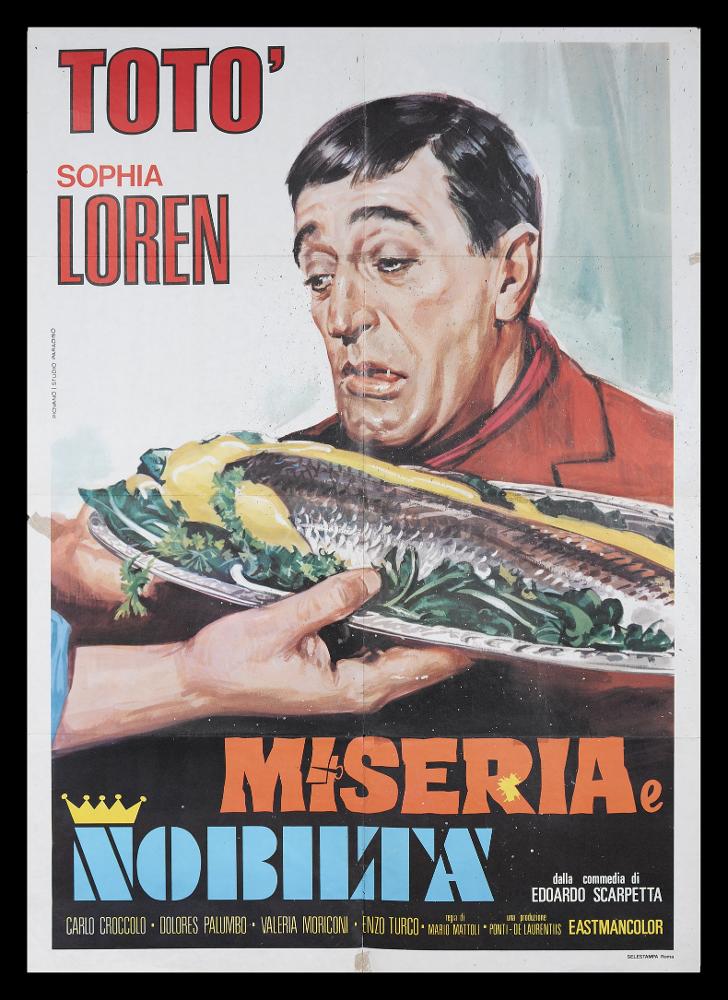 L'immagine riproduce uno dei manifesti conservati presso la Mediateca Regionale Pugliese (vedi Note). Si tratta di una delle versioni grafiche del manifesto del celebre film "Miseria e Nobiltà", con Totò e Sophia Loren. L’illustratore Mario Piovano realizza dagli anni ’60 con lo Studio Paradiso una serie di manifesti; qui riproduce in maniera pittorica una delle scene della commedia italiana del 1954, esaltando la figura dell’attore - assoluto protagonista insieme al cibo di tutto lo spazio compositivo - eseguendone un bel ritratto fedele che omaggia le espressioni mimiche tipiche di Totò. L’artista combina perfettamente così le peculiarità del film, incentrato sul gioco degli equivoci e il tema della fame secolare, che fu di Pulcinella. Intorno alla figura e nella part...