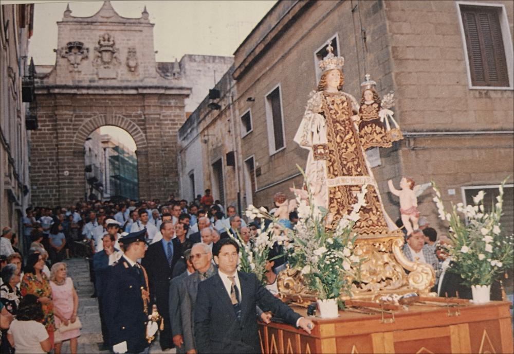 <div class="ql-editor"><div>L'immagine digitale immortala la statua votiva della Madonna del Carmine avanzare in processione per le vie della città di Mesagne (BR), attorniata da una folla di fedeli, nella data del 17 luglio 2006.</div><div>La Festa Patronale della Madonna del Carmine, celebrata dal 15 al 17 luglio fin dal 1651, è uno degli eventi più significativi per la comunità. Non è soltanto una ricorrenza religiosa, ma un rito collettivo che rinnova ogni anno tradizioni, legami e identità.</div><div>Il 15 luglio si svolge la solenne processione che accompagna il simulacro della Vergine dalla Basilica del Carmine alla Chiesa Matrice, alla presenza di confraternite, autorità religiose e civili, bande musicali e numerosi fedeli. In ...