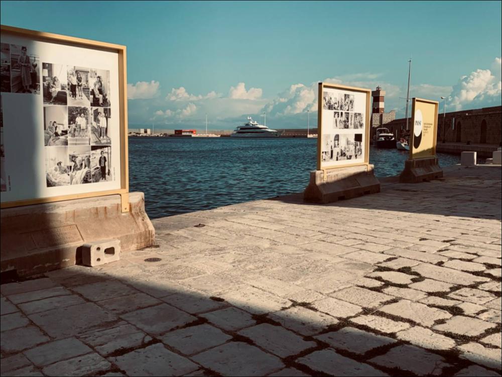 Il Porto vecchio di Monopoli è stato allestito con pannelli permettendo di mettere in mostra il collage “temporale” di Nancy Floyd (Minnesota, 1956) dal titolo "Weathering Time".  È un’artista visiva, una fotografa che riesce ad immortalare il tempo nei suoi scatti da oltre 40 anni, mettendo in evidenza l’invecchiamento del corpo femminile, il trascorrere del tempo e il rapporto dell'uomo con l’ambiente. Il risultato ottenuto è un calendario visivo composto da oltre 2.500 fotografie, dove il movimento del mare si mescola con il lento sfogliare delle pagine di questo immenso album personale.
“Se Weathering Time racconta la mia giovinezza fino all’inizio della mia età matura, le immagini riflettono anche le esperienze della mia generazione e sottolineano i cambiamenti cul...