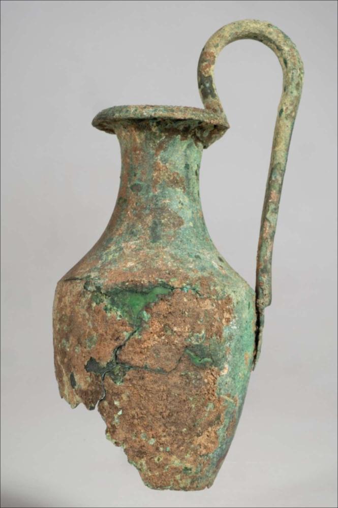 <div class="ql-editor"><div>L’olpe in bronzo appartiene a un gruppo di reperti di generica provenienza da Soleto, entrati nelle collezioni museali nella seconda metà dell’Ottocento e acquisiti al patrimonio dell’allora Provincia di Terra d’Otranto. I reperti furono inventariati e sistemati museograficamente solo all’inizio del 1928, nell’ambito del riordino delle collezioni. Il vaso presenta un orlo espanso e ribattuto verso l’esterno, un alto collo concavo, una spalla carenata e un corpo ovoidale. L’ansa verticale, a bastoncello e fortemente sormontante, termina sotto la spalla con un’applique a palmetta capovolta, impostata su volute. Il bordo superiore è decorato da un sottile filetto perlinato.</div></d...
