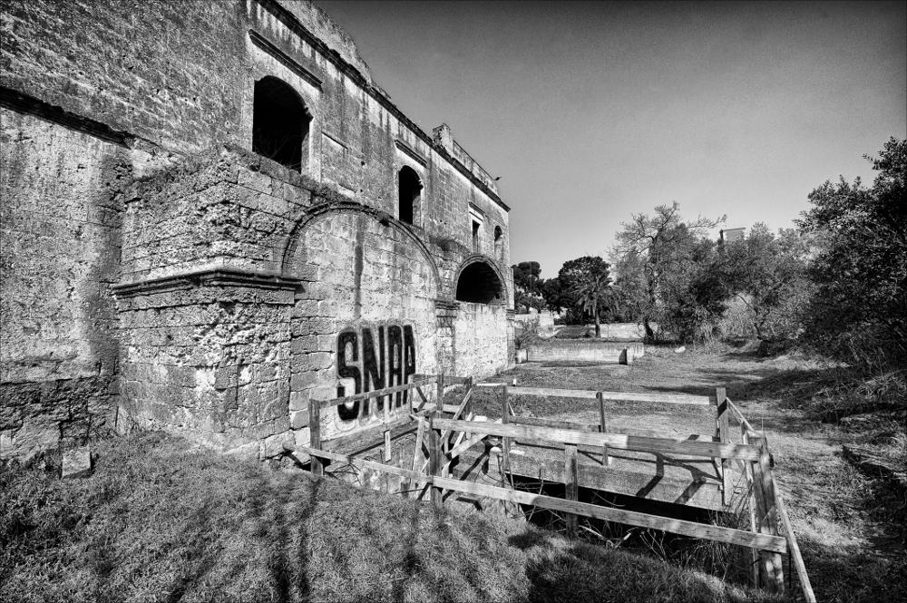 La fotografia è parte di una più ampia raccolta di fotografie realizzate per il progetto di censimento di 248 masserie pugliesi avviato da Giancarlo Chielli, professore del corso in Beni Culturali e Ambientali presso l'Accademia di Belle Arti di Bari. Il lavoro svolto ha dato vita al volume “Le masserie di Puglia come Bene Culturale” in cui sono presenti alcuni scatti di masserie pugliesi tra cui quella in oggetto. Situata in pieno contesto urbano, sul cavalcavia che unisce Viale Papa Giovanni XIII e Viale Pasteur a Bari dove un tempo si trovava la lama Lamberti, la masseria si presenta in evidente stato di abbandono. È una possente architettura rettangolare, a blocco compatto su due livelli distinti da un marcapiano, tipica del Settecento, un tempo posseduta dalla fami...