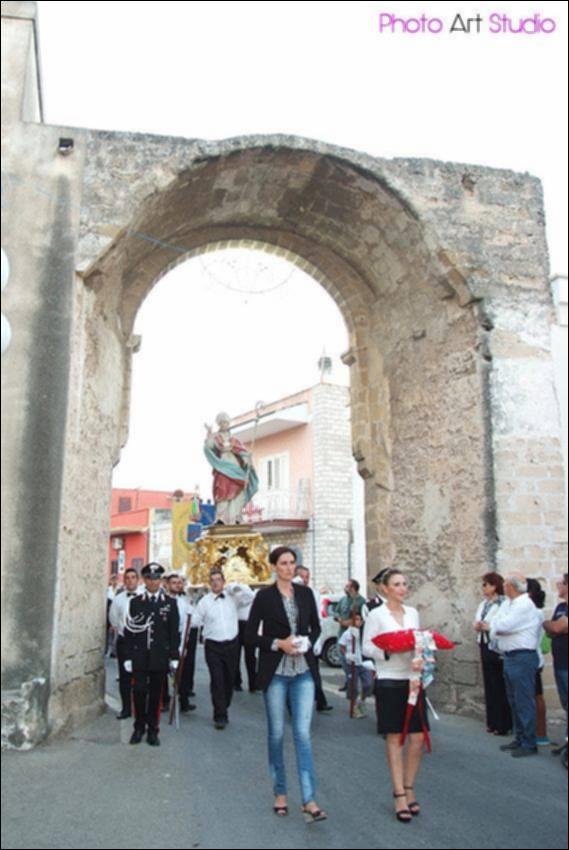 <div>La fotografia mostra la processione di <strong>Sant’Emidio</strong> mentre attraversa l’arco di Porta Taranto, uno dei passaggi simbolici del centro storico di Leporano. La festa patronale di Sant’Emidio, molto attesa dalla comunità locale, rappresenta uno dei momenti centrali della vita religiosa e sociale del paese.</div><div><br></div><div>Porta Taranto è una delle porte d'ingresso al centro storico del paese, ancora rimasta,e fa parte della cinta difensiva con alcuni bastioni rettilinei e torri cilindriche del castello Muscettola.</div><div><br></div><div>Il programma dei festeggiamenti si articola in una <strong>novena preparatoria</strong>, con celebrazioni liturgiche quotidiane animate dai diversi gruppi parrocchiali, cui seguono ...