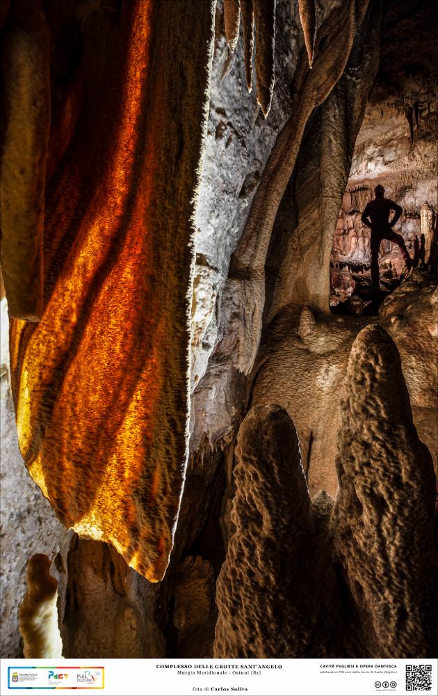 Siamo all’interno delle Grotte di Sant’Angelo, presso Ostuni, nelle Murge meridionali.
La luce penetra insolentemente in una sottile vela calcarea che sembra, all'improvviso, prendere fuoco. Difficile districarsi in questo angosciante mondo sotterraneo dove imponenti ammassi stalagmitici sbarrano la strada e dove le gelide pareti rocciose, come quinte di un sipario, occultano gelosamente la scena agli occhi degli intrusi.
L’immagine digitale fa parte della raccolta di fotografie prodotte da Carlos Solito per il Progetto digitale “Sillabario sotterraneo – Viaggio dantesco nelle Grotte di Puglia” – realizzato nell’ambito della LEGGE REGIONALE 30 dicembre 2020, n. 35 - art. 39 “Cavità pugliesi e opera dantesca - Celebrazioni 700 anni dalla morte di Dante Alighieri”.